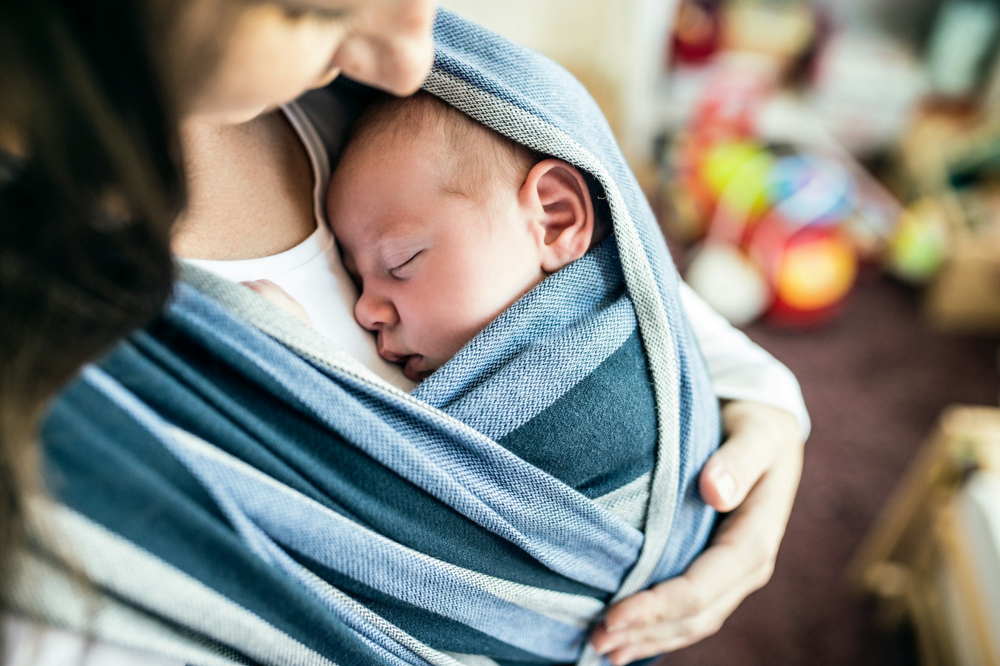 Unrecognizable young mother with her son in sling